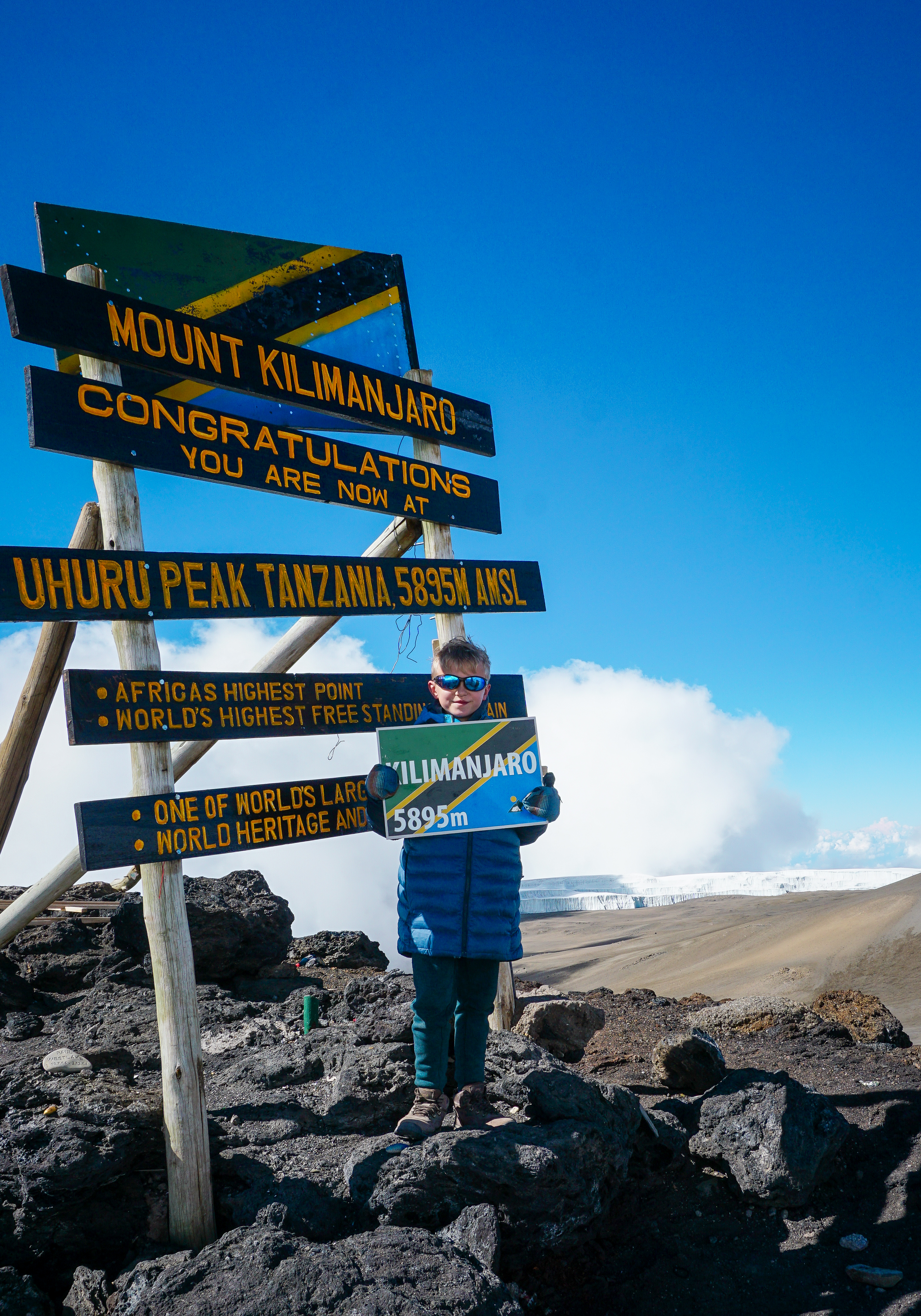 .A young hiker displays the Tanzanian flag at the summit of Mt. Kilimanjaro
