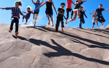 Kids jump and slide on the crest of a singing sand