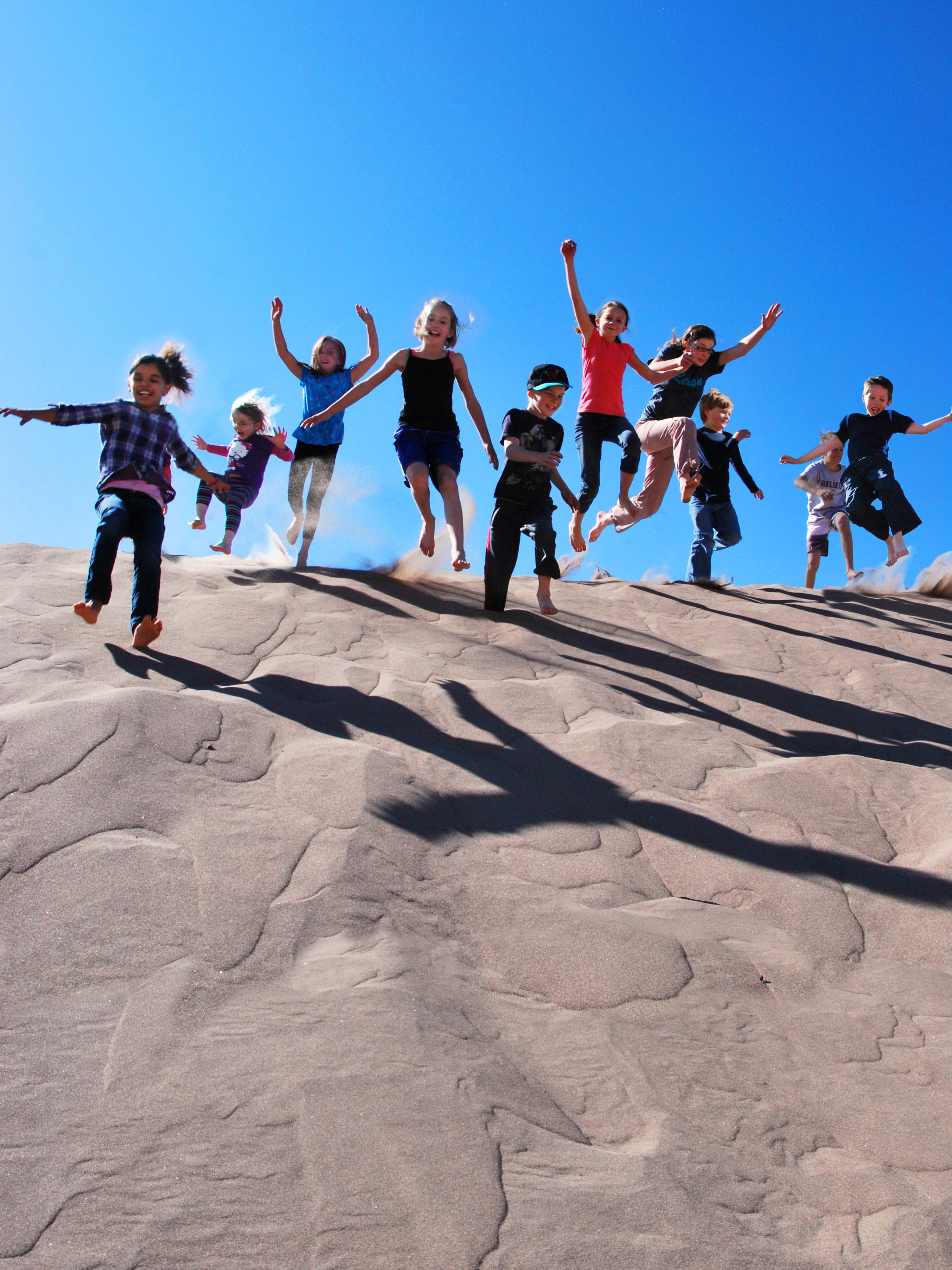 Kids jump and slide on the crest of a singing sand