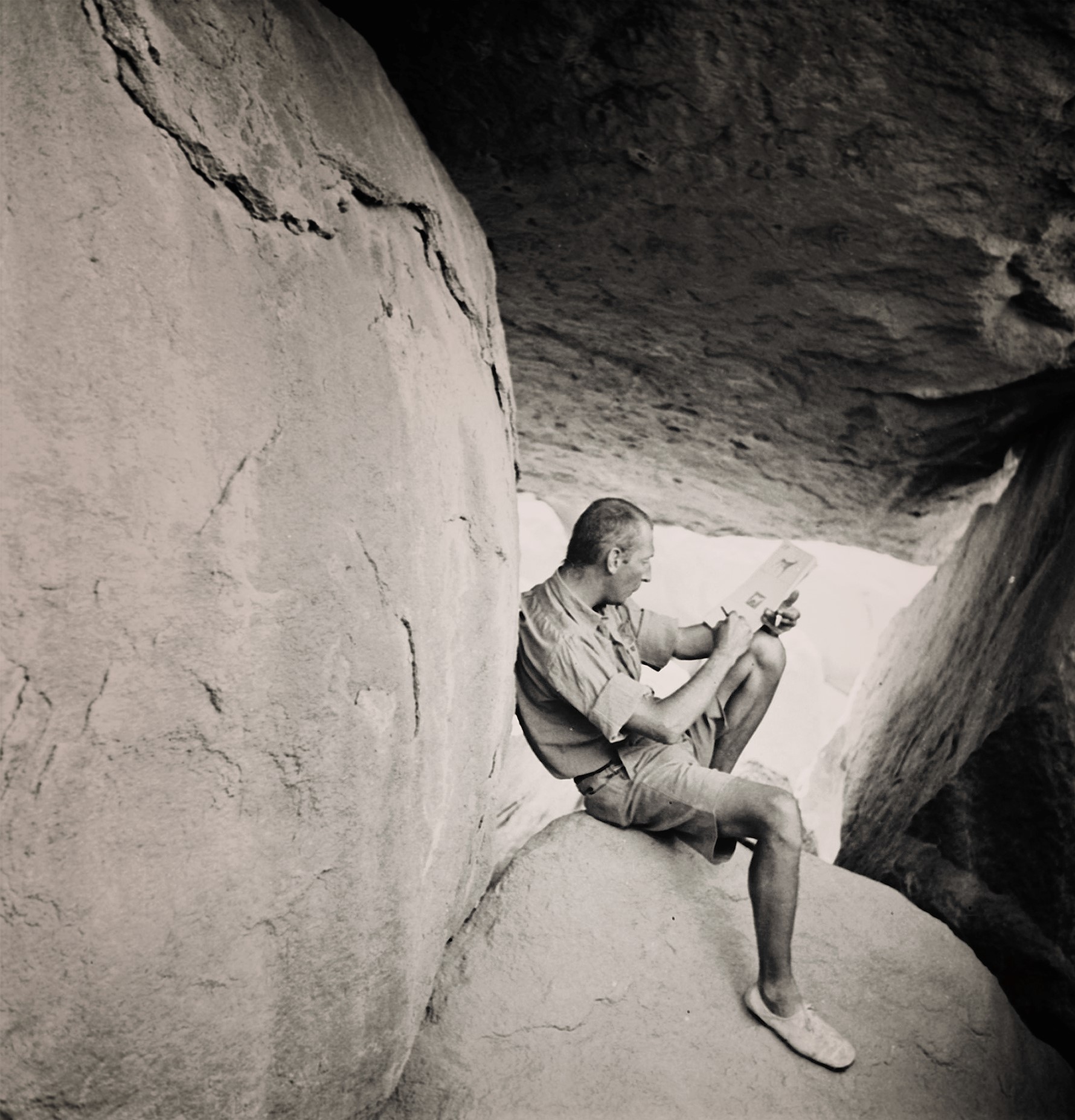 László Almásy sitting on a desert rock outcrop in the 1930s.