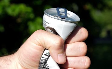 Aluminum can being crushed by hand