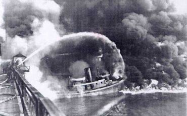 Firemen stand on a bridge over the Cuyahoga River in November 1952 to spray water on the tug Arizona